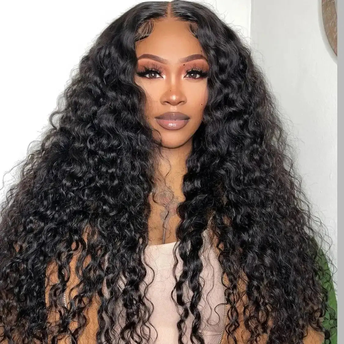 Woman with long, curly black hair wearing a brown jacket.