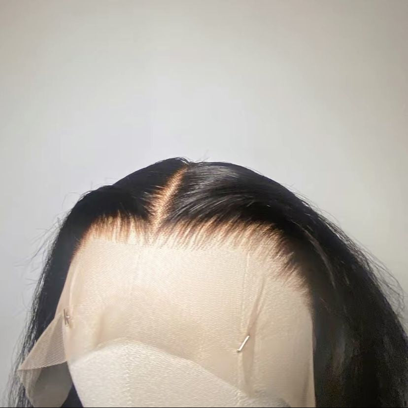 Black hair wig on a mannequin head against a plain background