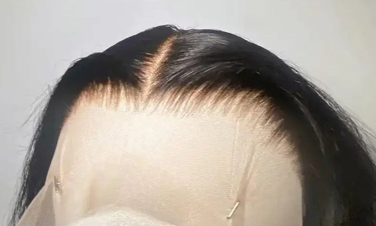 Black wig on a mannequin head against a plain background